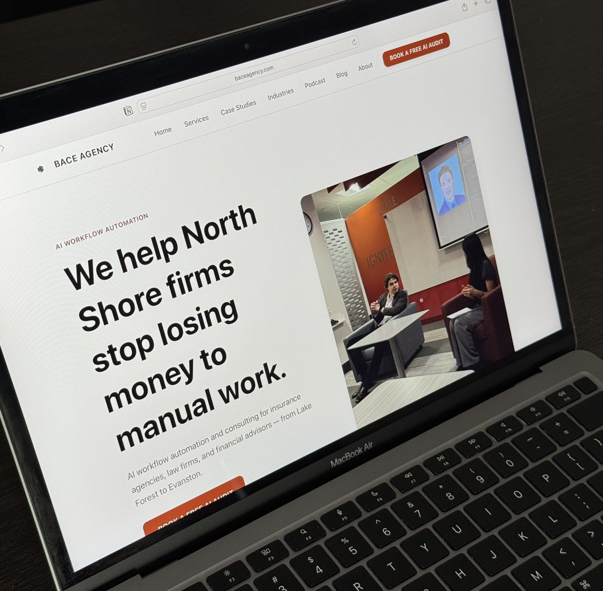 A MacBook Air on a desk showing the Bace Agency homepage with the headline We help North Shore firms stop losing money to manual work.