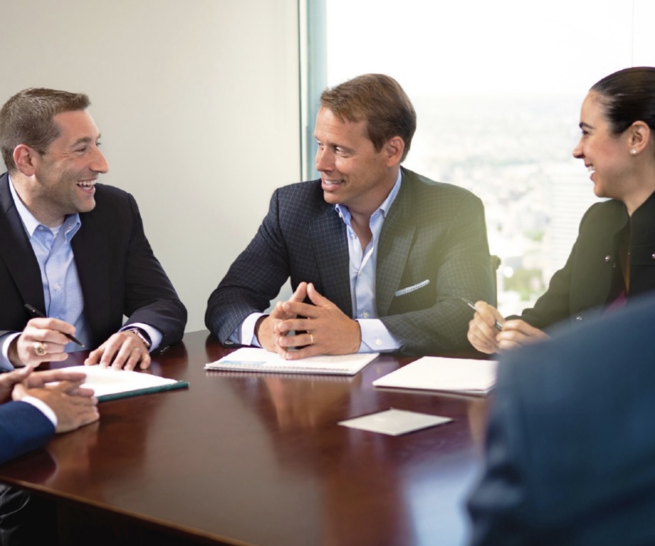 Senior M&A advisors analyzing financials and discussing deal strategy during a corporate meeting.