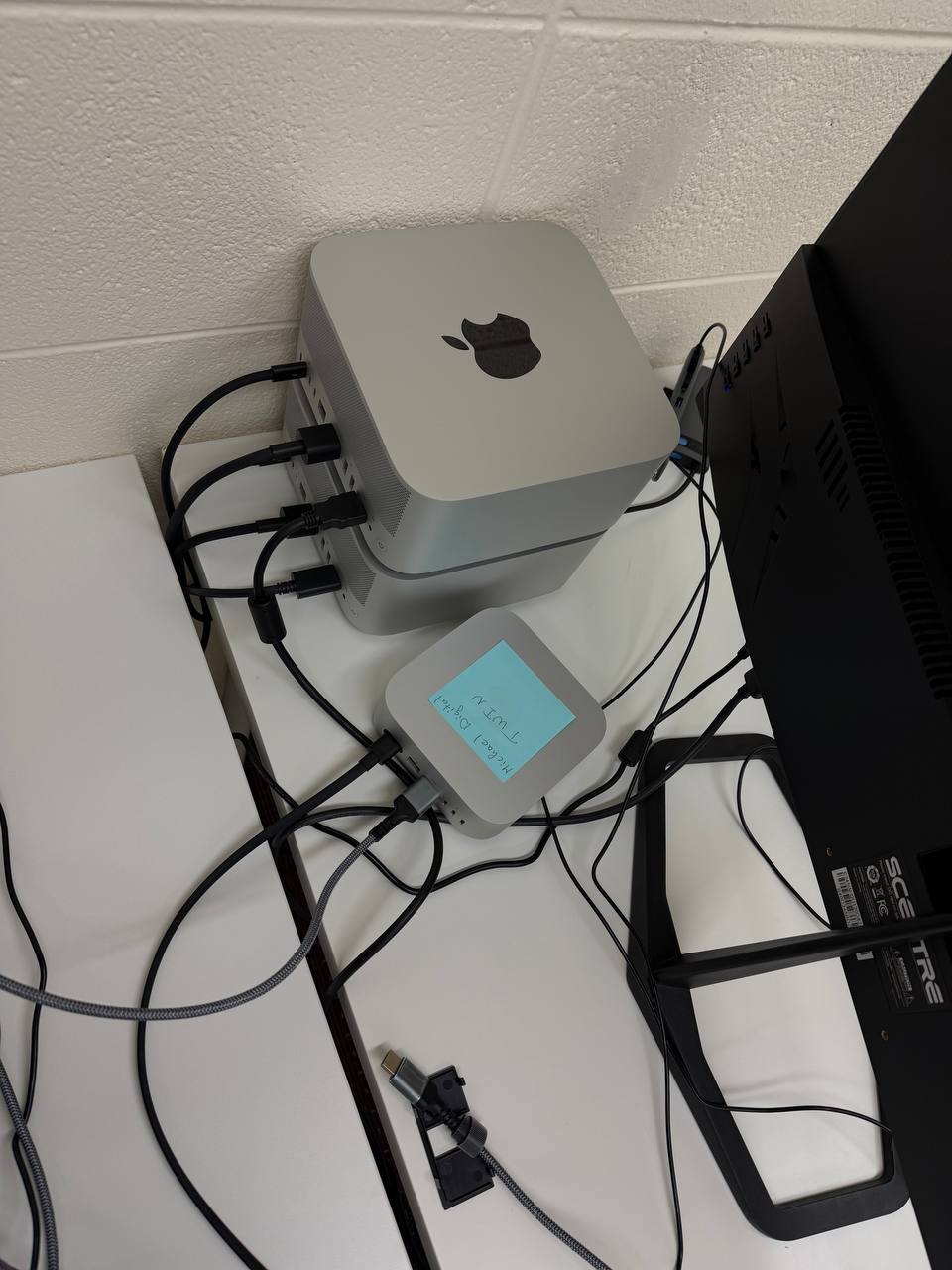 Two Mac Studios stacked on a desk, wired into a hub, running local AI models