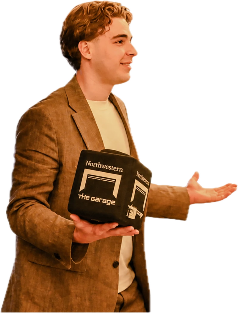 Michael Pavlovskyi speaking at Northwestern's The Garage, holding the Garage cube